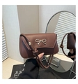 Detail of a brown shoulder bag featuring a gold bow accent and reflective mirror finish - Brown