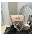 Detail of light beige baguette bag featuring a gold metal bow and knotted rope strap - Khaki
