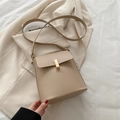 Minimalistische beige Leder-Schultertasche mit goldener Schnalle auf cremefarbenem Sakko - Khaki