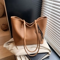 Brown leather tote bag with FASHION embossing and woven charm on beige jacket background - With Pendant / Brown