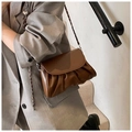 Detail van de donkerbruine geplooide crossbodytas met ketting op een grijze blazer - Bruin