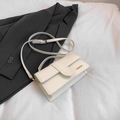 Elegante weiße Umhängetasche aus Leder mit Gold-Hardware auf einem grauen Blazer - Weiß