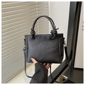 Detail der schwarzen Handtasche aus Leder mit Lychee-Maserung und modischer Logo-Prägung - Schwarz