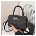 Dettaglio di mini borsa nera glitterata con fiocco argentato e tracolla in pelle fine - Nero