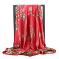 Red silk-like scarf featuring leopard and gold chain print hanging on a black stand - New Red