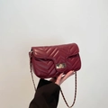 Burgundy quilted shoulder bag with gold twist lock and leather chain strap in hand - Burgundy