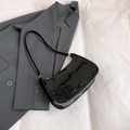Glossy black patent leather baguette shoulder bag on a grey blazer for a retro style - Black