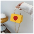 Detail of yellow crossbody bag with red heart patch and elegant white pearl handle - Yellow