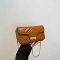 Brown quilted crossbody bag with V-shaped stitching and gold chain strap in hand - Brown