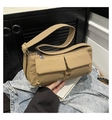 Detail view of khaki nylon crossbody bag with dual front pockets on denim jacket - Brown