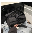 Detail of black quilted shoulder bag with two front pockets on a denim jacket - Black