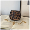 Dettaglio della borsa a sella leopardata con catena dorata su uno sfondo di libro estetico - Marrone
