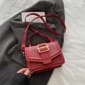 Borsa a tracolla in pelle rossa opaca con elegante fibbia dorata su giacca grigia - Rosso