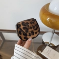 Mini leopard print crossbody bag with gold chain strap shown in a vintage artistic setting - Brown