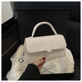 Détail d'un sac à main blanc en cuir avec rabat en V et coutures verticales en main - Blanc