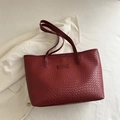 Elegante borsa tote intrecciata bordeaux con spalline sottili su una giacca bianca - Rosso