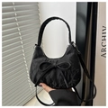 Detailed view of black pleated dumpling bag with large bow and texture detail - Black