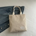 Minimalist beige corduroy tote bag with woven handles and white oval brand logo detail - Khaki