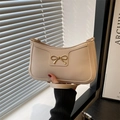 Chic beige crescent underarm bag featuring a gold metal bow and sleek zipper design - White