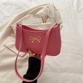 Rosa Halbmond-Achseltasche mit goldener Schleife auf minimalistischem Blazer-Hintergrund - Rosa