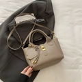 Taupefarbene Eimertasche aus Leder mit Griff, Umhängeriemen und niedlichem Bärenanhänger - Khaki