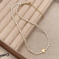 Detail view of a pearl necklace featuring a golden heart pendant and lobster clasp closure - Gold Heart Pendant High Luster Pearl Chain