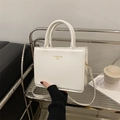White square faux leather crossbody bag with gold Fashion Bag text and round handles - White