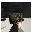 Close-up of black and gold tweed texture with metallic chain on a stylish shoulder bag - Black