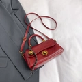 Retro deep red crossbody bag with gold lock and bell charm on a gray blazer - With Pendant / Red