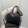 Borsa tote minimalista in pelle nera opaca su una sedia con cappotto di lana e libro - Nero