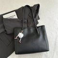 Detail of black matte leather tote bag with white plush charm and decorative stitching - Black With Pendant