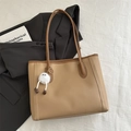 Detail of light khaki tote bag with plush charm, styled with blazer and book - Khaki With Pendant