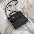 Minimalist black square crossbody bag with gold buckles and top handle on white linen - Black