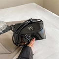 Elegant black patent leather crossbody bag with golden bow clasp and woven strap - Glossy Black
