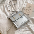 Metallic silver square handbag with gold buckles on a white textured background - Silver
