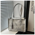 Dettaglio della borsa tote argento con ricamo a farfalla ed elegante ciondolo con nappina - Argento