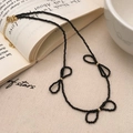 Dettaglio macro della collana di perle nere con fiocco e chiusura in oro su libro - Oro