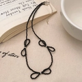 Vista macro di una collana di perle nere con tre fiocchi delicati e chiusura in argento - Argento