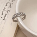 Macro shot of silver open ring with zircons and pearls hanging on a white ceramic bowl - Silver