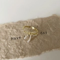 Makro-Detail des goldenen Schleifenrings mit Zirkonia-Besatz und kleinen Perlen - Gold