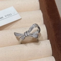 Detalle de un anillo con lazo de circón brillante presentado en un soporte de terciopelo - Anillo de Lazo / Plateado