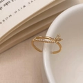 Detalle de anillo dorado con mariposa y perlas blancas sobre un borde de cerámica - Dorado