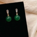 Detailopname van groene chalcedoon oorbellen met zirkonia op een fluwelen standaard - Gouden Groene Chalcedoon Hangende Oorbellen