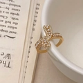 Dettaglio anello a fiocco dorato con perle e zirconi appoggiato su una ciotola di ceramica - Anello Fiocco Zircone Perla / Oro