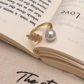 Detail view of gold open ring featuring a sparkling leaf motif and white shell pearl - Gold Peacock Feather Pearl Ring