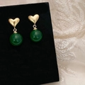 Dettaglio di orecchini a cuore in oro con perle di calcedonio verde su velluto nero - Orecchini a Cuore Oro e Calcedonio Verde / Oro