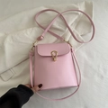 Pink faux leather mini crossbody bag with a gold U-shaped lock on textured background - Pink