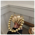 Detail van een gouden avondtas in de vorm van een schelp met een handvat van gouden kralen - Schelpgoud