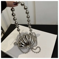Macro view of silver shell-shaped mini bag with metallic chrome finish and pearl handle - White Shell Silver