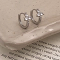 Detailed view of silver hoop earrings with zircon petal design on a vintage book - Silver With White Flower (White Zirconia)
